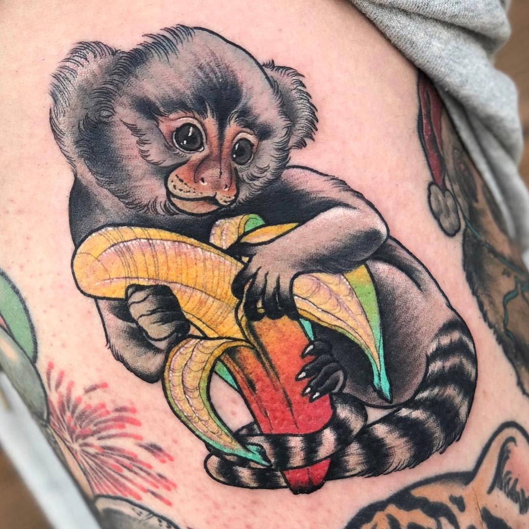 Tattoo of a monkey holding a peeled banana on skin